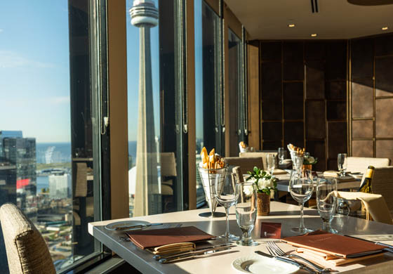 Table setting in Stratus Restaurant, with views of the CN Tower and Lake Ontario in the background